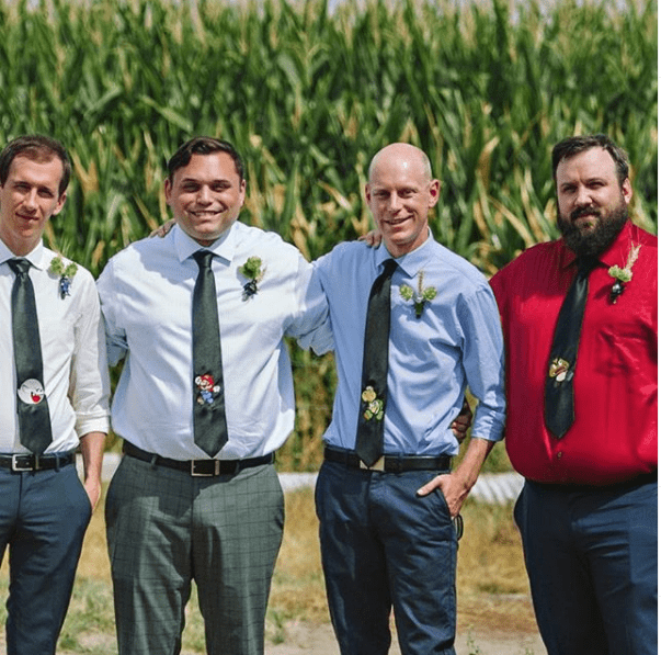 A group of groomsmen, stylishly dressed in Custom Wedding Ties, standing in front of a corn field.