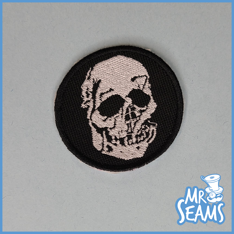 A black and white patch with a skull on it.