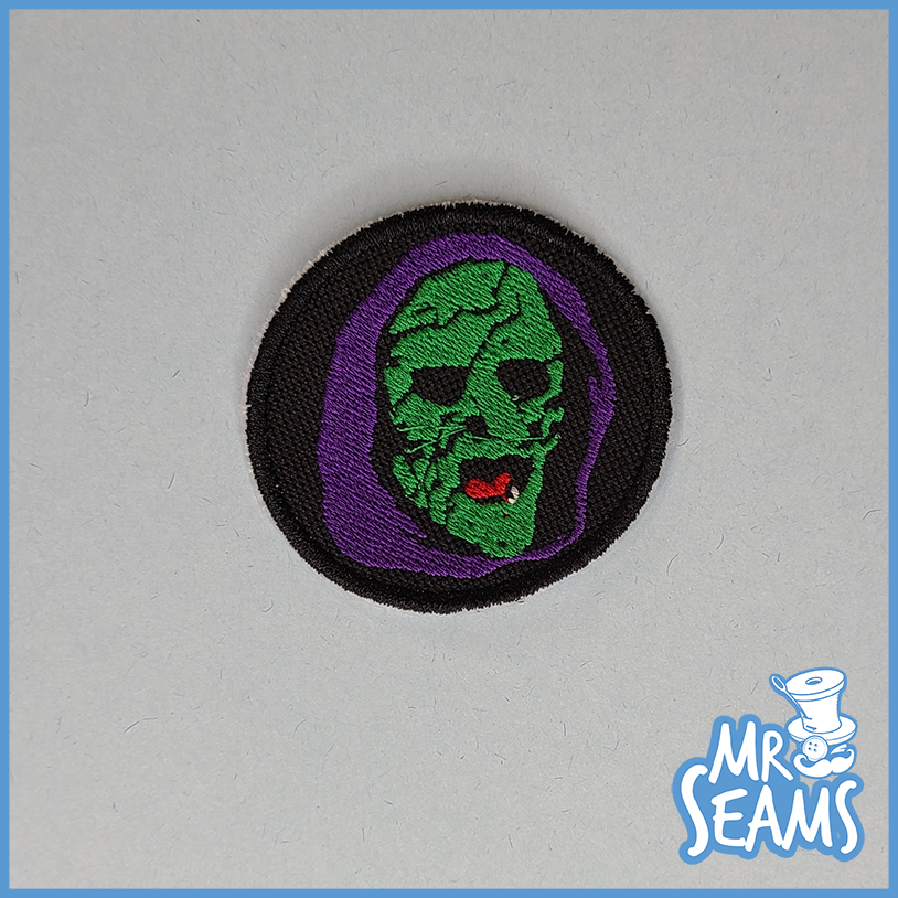 A patch with a green and purple face on it.