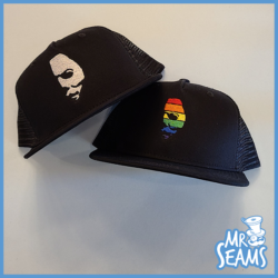 Two black Michael Pride Hats & Beanies with a face on them.