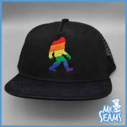 A black trucker hat with a bigfoot on it from Pride Sasquatch/Bigfoot Hats & Beanies is the product name.
