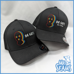 A black Be Gay Do Crime Hat with a rainbow face on it, perfect for those who love to be bold and embrace their individuality with the "Be Gay Do Crime" spirit.